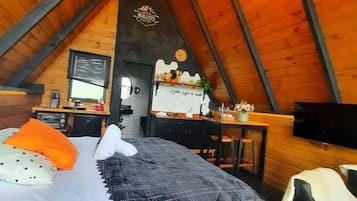 Een gezellig slaapkamer op zolder met een bed, een bureau, een televisie en een kroonluchter.