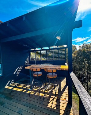 A wooden deck with a table and chairs, a railing, and a view of trees. - Refugio mirante da montanha (Alfredo Wagner)