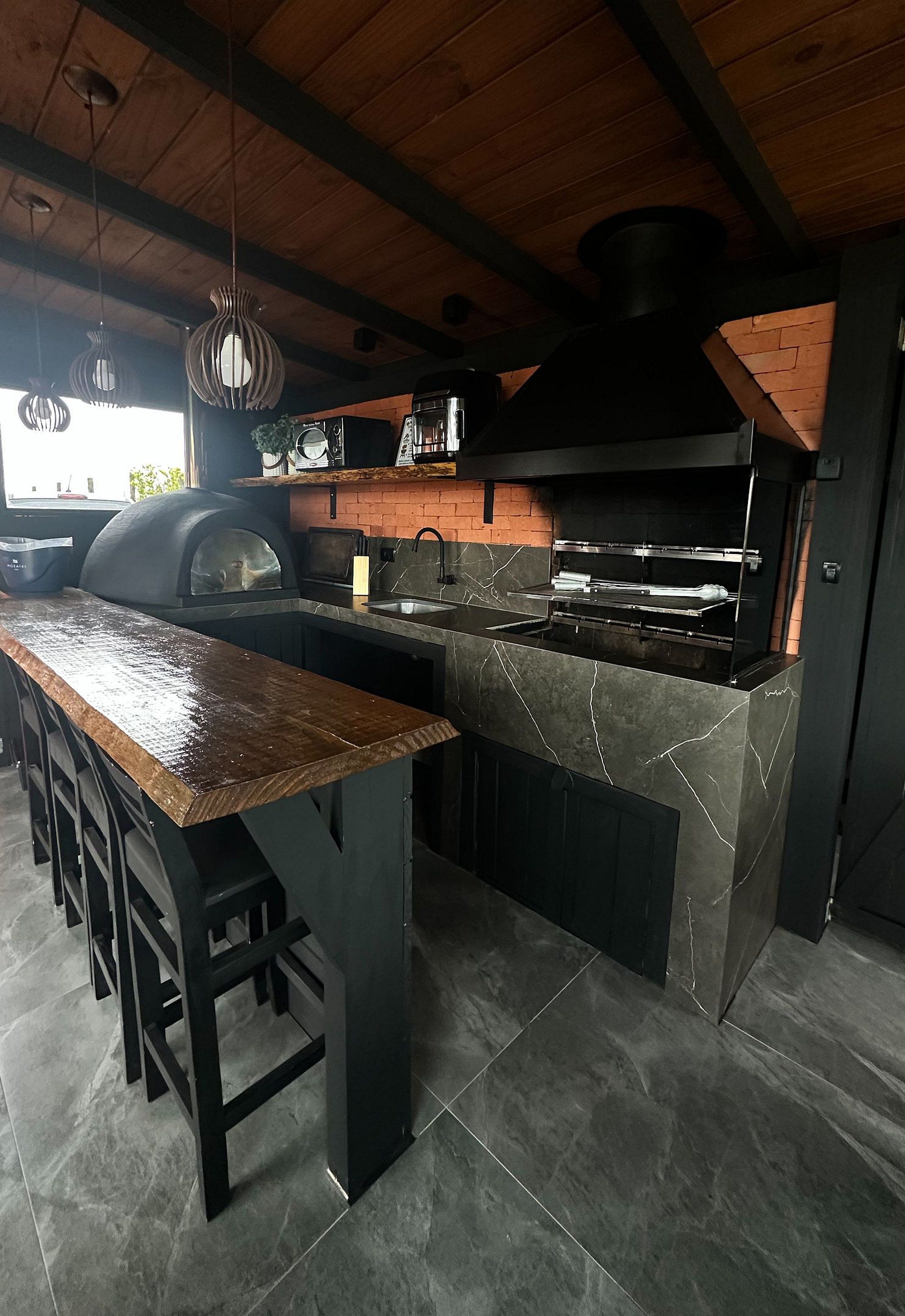 A kitchen with a wooden ceiling, a marble countertop, and a black stove.