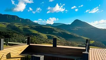 Eine Holzterrasse mit Whirlpool und Bergblick.