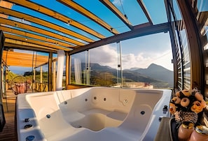 Ein Whirlpool mit Blick auf Berge, eine Holzterrasse und eine Glaseinfassung.