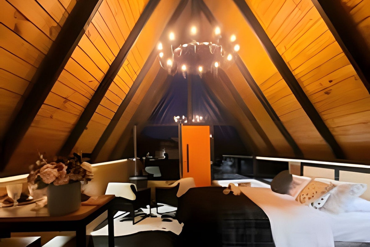 Un dormitorio acogedor en el ático con cama, mesa y silla.