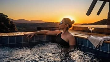 A person relaxing in a hot tub with a sunset view.