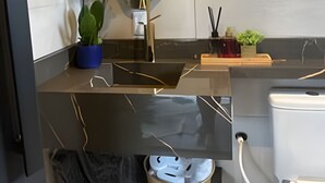 Une salle de bain moderne avec un grand miroir, un lavabo, des toilettes et une petite plante.