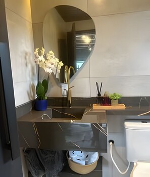 Ett modernt badrum med en stor spegel, ett handfat, en toalett och en liten växt.