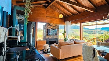 A modern kitchen with a gas stove, a stone fireplace, and a large window overlooking a scenic landscape.
