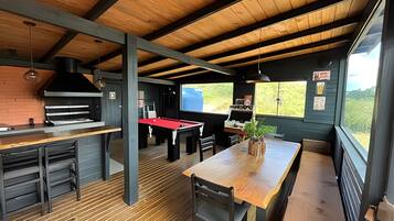 Decoração rústica com mesa de bilhar, espaço de bar e uma grande janela com vista para o verde.