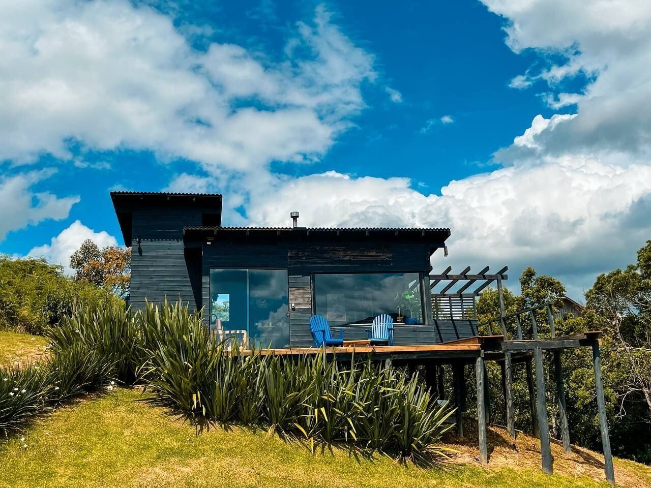 Een moderne chalet met terras, grote ramen en een pergola.