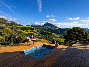 A wooden deck with a hot tub and lounge chairs overlooking a mountainous landscape. - Refugio mirante da montanha (Alfredo Wagner)