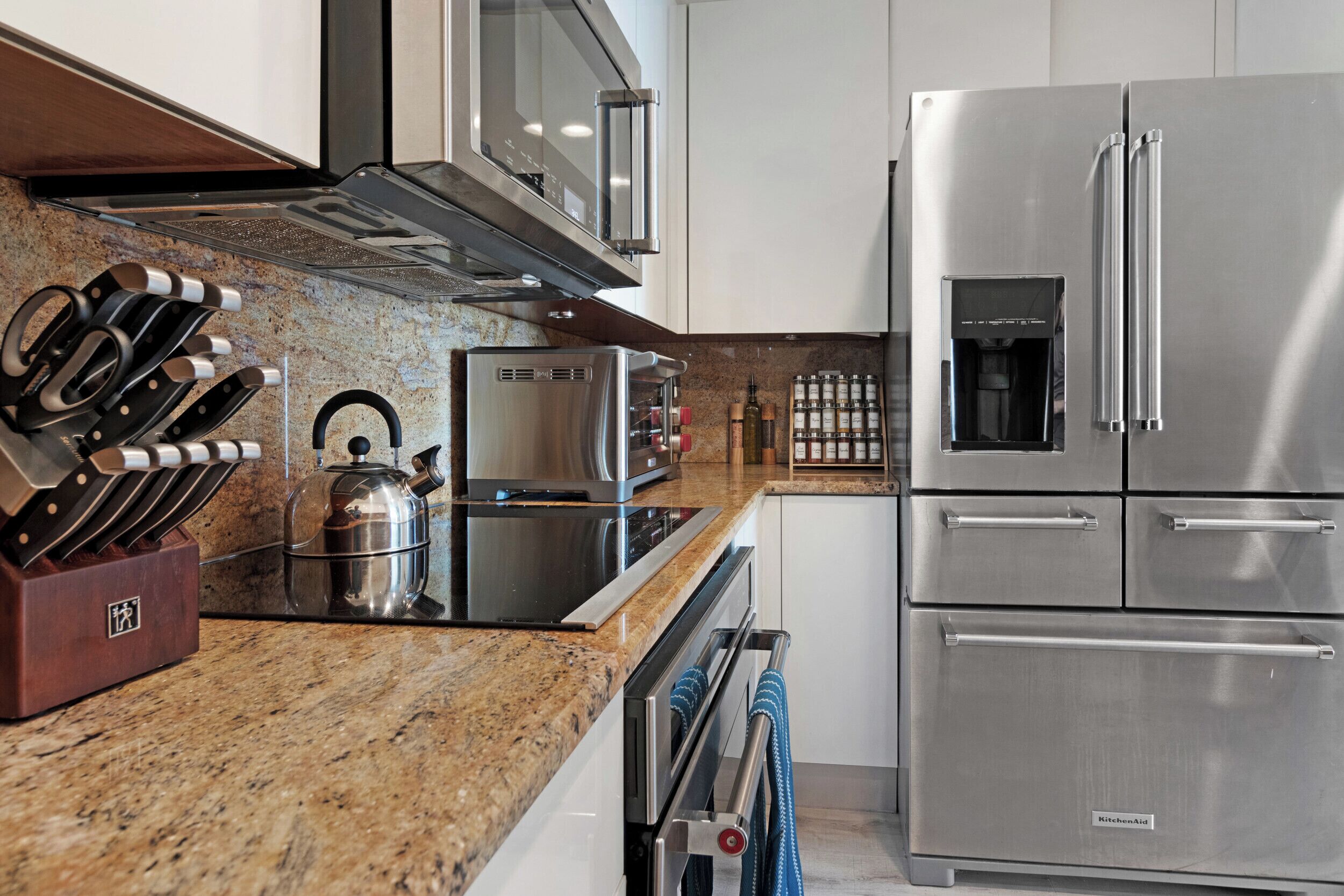 Una cocina moderna con electrodomésticos de acero inoxidable, encimera de granito y un bloque de cuchillos.