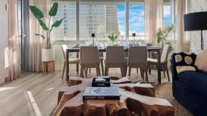 Een moderne woonkamer met een eethoek, grote ramen en uitzicht op hoge gebouwen.