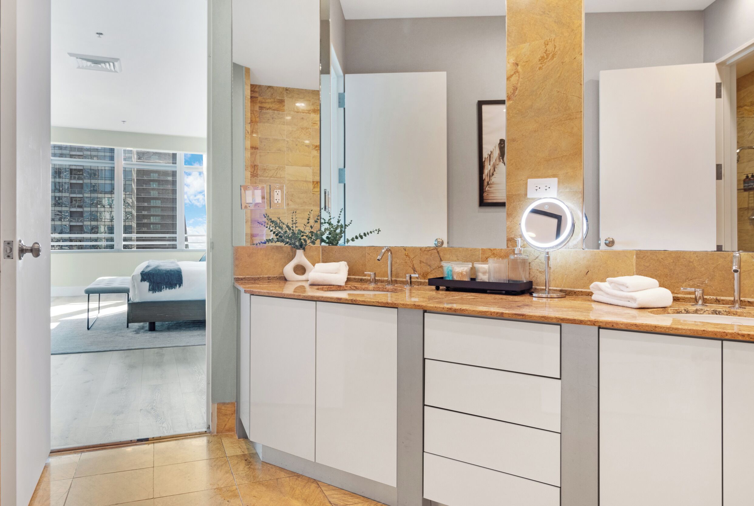 A modern bathroom with a large mirror, two sinks, and a vanity with drawers.