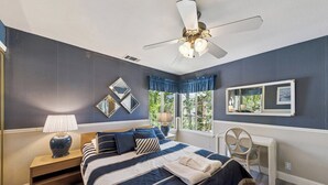 Camera da letto con un letto, un comodino, una lampada e una ventola a soffitto.