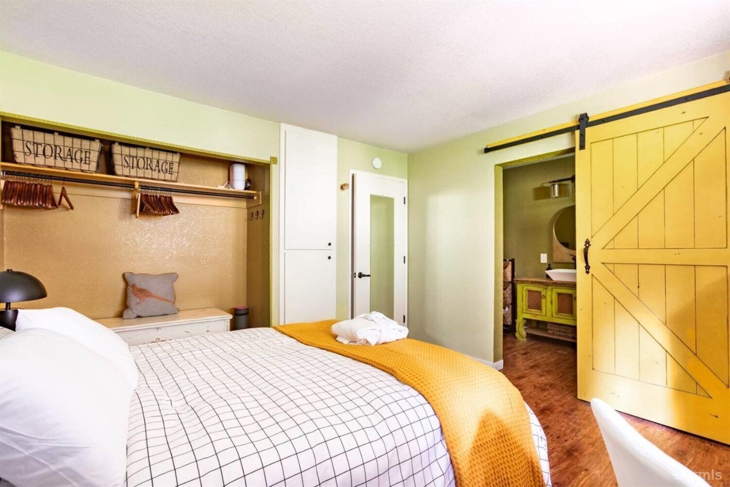 A bedroom with a bed, a storage unit, a wardrobe, and a bathroom visible through an open door.