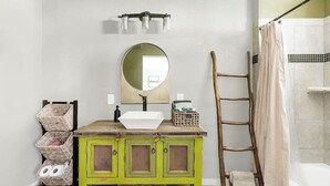 Une salle de bain avec un meuble-lavabo en bois, un miroir rond, un lavabo blanc et un rideau de douche.