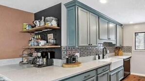 Une cuisine avec des armoires de couleur turquoise, un plan de travail blanc et un dosseret carrelé.