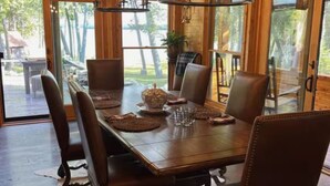 Un comedor de madera con una mesa grande, seis sillas y una araña.