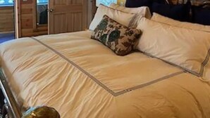 Un dormitorio con paneles de madera, una cama, almohadas y una mesita de noche.