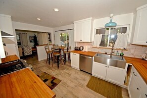Une cuisine moderne avec des meubles blancs, un plan de travail en bois et un lave-vaisselle encastré.