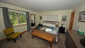 Un dormitorio con una cama, un banco, una silla, un tocador y una ventana con cortinas.