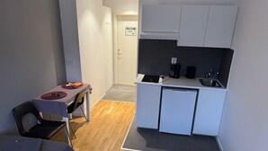 Pieni huone, jossa on pieni keittiö, ruokailutila ja kaksi sänkyä.