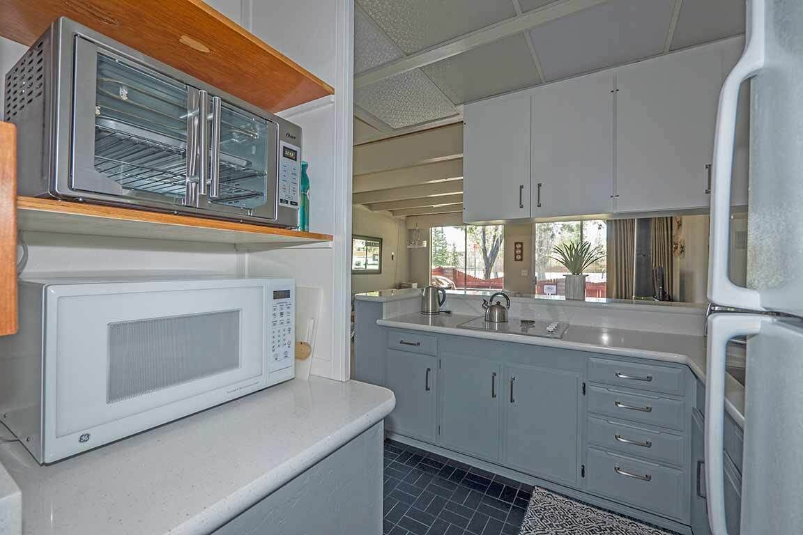 A compact kitchen with white cabinets, a microwave, and a built-in oven.