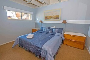 Una camera da letto con un letto, un comodino, una cassettiera, una finestra e un quadro appeso al muro.