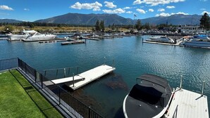A marina with boats docked, a grassy area, and mountains in the background.
