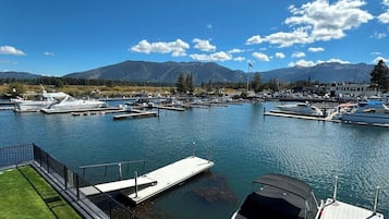 Un port de plaisance avec des bateaux amarrés, une zone herbeuse et des montagnes en arrière-plan.