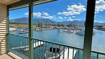 Une terrasse couverte offrant une vue sur un port de plaisance et les montagnes.