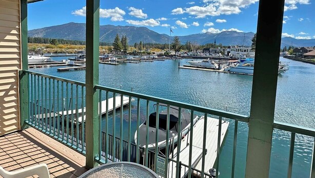 A covered deck with a view of a marina and mountains.