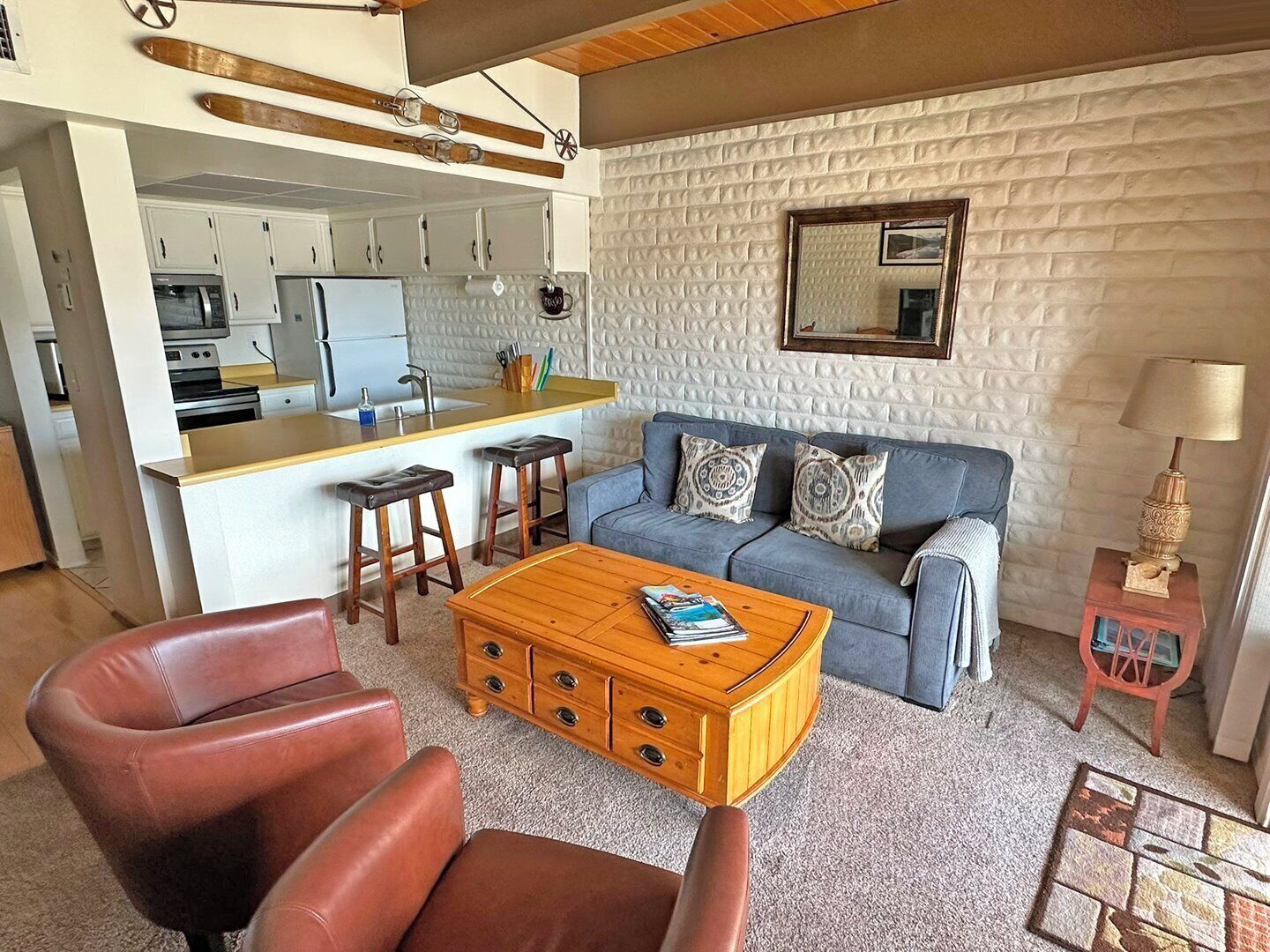 A compact living space with a kitchenette, a sofa set, a coffee table, and a small side table.