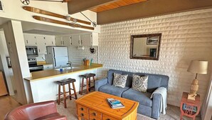 A compact living space with a kitchenette, a sofa set, a coffee table, and a small side table.