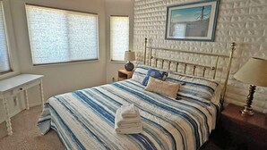 A bedroom with a bed, a desk, and a window.