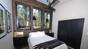 A bedroom with a large window, a bed, a nightstand, and a wardrobe. - Penthouse Retreat with Mountain Views & Designer Touches (South Lake Tahoe)