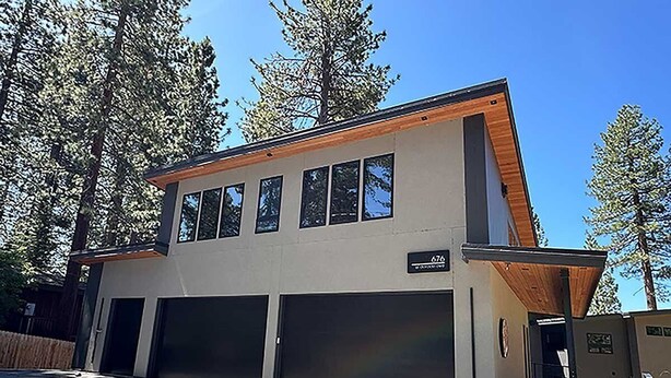 A modern two-story house with a garage, surrounded by tall trees. - Penthouse Retreat with Mountain Views & Designer Touches (South Lake Tahoe)
