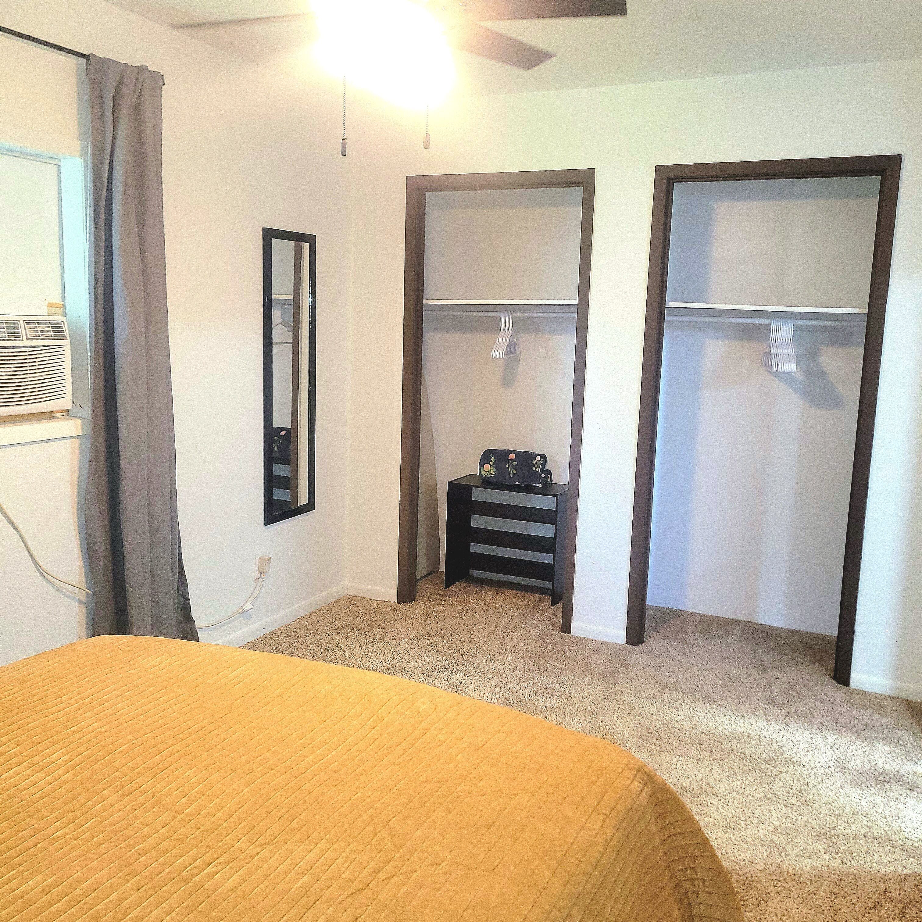 A bedroom with a bed, a wardrobe, a mirror, and a heater.