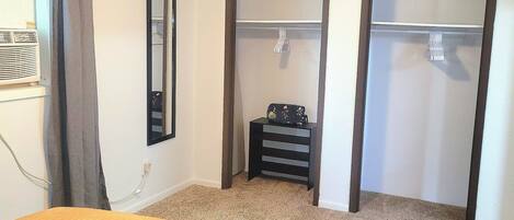 A bedroom with a bed, a wardrobe, a mirror, and a heater.