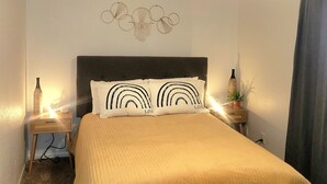 Un dormitorio con cama, dos mesitas de noche, un ventilador de techo y una decoración en la pared.