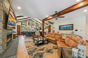 A spacious living room with a fireplace, leather sofa, and a large TV.