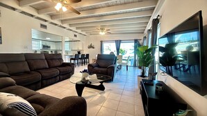 A modern living room with a sofa, armchair, coffee table, and a TV. - Paradise House a Waterfront Oasis : Your Perfect Getaway on the Atlantic! (Marathon)