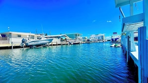 A marina with boats docked, a covered area, and a building with a balcony. - Paradise House a Waterfront Oasis : Your Perfect Getaway on the Atlantic! (Marathon)