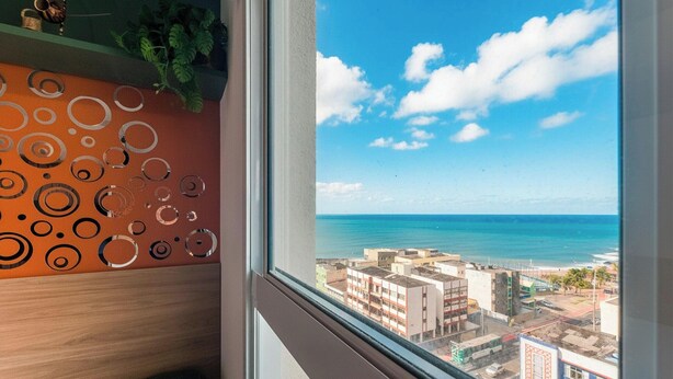 A view from a window overlooking a coastal cityscape with buildings and the ocean. - Your Complete Stay in Salvador, Steps From the sea - Saas (Salvador)