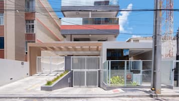 Un bâtiment moderne doté d’une entrée sécurisée par un portail, d’un espace abrité et d’un escalier apparent menant à un étage supérieur.