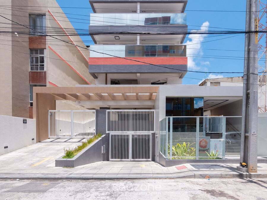 Un bâtiment moderne doté d’une entrée sécurisée par un portail, d’un espace abrité et d’un escalier apparent menant à un étage supérieur.