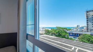 A view from a window of a building with a metal roof, a balcony, and a clear blue sky.
