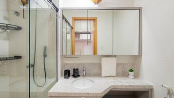 Une salle de bain moderne avec une douche à parois de verre, un lavabo blanc et un grand miroir au-dessus du meuble-lavabo.