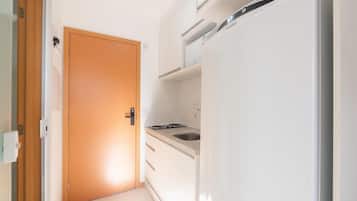Een kleine keuken met een inbouwkoelkast, een fornuis en een spoelbak.