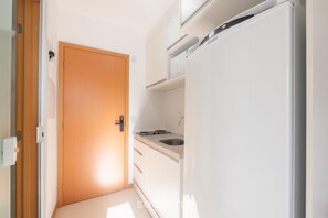 A compact kitchen with a built-in refrigerator, a stove, and a sink. - Your Complete Stay in Salvador, Steps From the sea - Saas (Salvador)