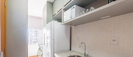 A modern kitchen with white cabinets, a stainless steel sink, and a window overlooking a balcony.